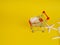 supermarket trolley on yellow background, shells inside, release, Concept of shopping. Copy space for advertisement.
