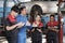 A supervisor engineer is training mechanic workers about car repair at a garage.