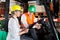 Supervisor Showing Clipboard To Colleague Sitting