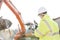 Supervisor using walkie-talkie at construction site against clear sky