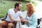 Supportive mature couple in wheelchairs chatting and smiling