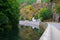 Sure river in Esch-sur-Sure, Luxembourg, with reflections and green vegetation at one side and the stone wall and road in the