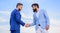 Sure sign you should trust business partner. Men formal suits shaking hands blue sky background. Business deal approved