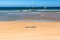 Surf board on the sand with surfers on waves at the distance