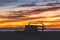 Surf boards silhouetted against vibrant yellow orange sky with clouds at sunset