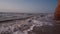 Surf of the brown, dirty sea, lonely beach, waves, clay rock, sky