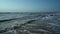 Surf of the brown, dirty sea, lonely beach, waves, sky