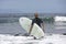 The surf enters the water. Male surfer entering the sea with his board in a black surfing suit. Tenerife, Spain. Surfer entering t