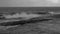 Surf on a rocky shore and hail. Black and white. Slow motion