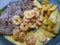 Surf and Turf recipe consisting of grilled steak fillets, cooked shrimps, potato fries, and a creamy cheese sauce