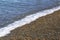 Surf wave on the beach with sea pebbles.