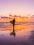 Surf woman with surfboard on a beach at sunset or sunrise.