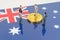 On the surface with the image of the flag of Australia are bitcoins and miniature figurines of people