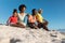 Surface level view of african american family sitting on sand at beach against clear blue sky