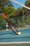 Surface level view of ball by racket leaning on tennis net at court during sunny day