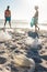 Surface level view of plastic garbage scattered against african american couple cleaning beach