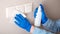 Surfaces disinfection. Houseworker in rubber blue gloves clean light switch with cloth on wall by alcohol spray and rag. New