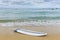 Surfboard lying on sand near the ocean