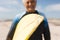 Surfboard with sand held by smiling biracial senior woman at beach during sunny day