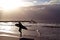 Surfer along the beach at sunset