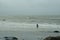 Surfer approaching to the wavy water during bad stormy irish weather.