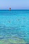 Surfer on board with sail floats on blue water of sea near shore