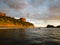 Surfer on board waiting for a ride in the ocean off hilly coast of Magnific Rock, Nicaragua in front of two houses