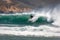 Surfer catches a tall wave with strong offshore breeze