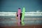 Surfer couple on the beach with a surfing board