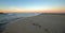 Surfer on dawn patrol with sunrise view of Santa Clara river flowing into Pacific ocean at Ventura California