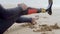 Surfer with disability sitting on shore and kneading legs