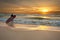 Surfer entering the ocean at sunrise