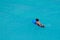 Surfer girl with afro hairstyle paddling out on surfboard in crystal clear turquoise water