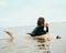 Surfer girl with Christmas red ball walking on the beach. New Year celebration in the ocean.