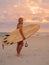 Surfer girl on sand beach with surfboard at warm sunset or sunrise. Attractive surfer on beach