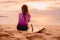 Surfer girl with surfboard on a beach at sunset