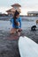 Surfer Girl. Surfing Woman On Sandy Beach With Surfboard And Dog. Asian Female In Blue Wetsuit Going To Surf In Ocean.