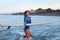Surfer Girl. Surfing Woman Walking Out Of Ocean. Smiling Tanned Brunette In Blue Wetsuit With Surfboard In Sea.