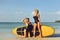 Surfer girls posing with surfboard on a beach