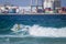 Surfer, going down a wave in Playa Blanca, Fuerteventura, Spain. We can see the Port of the town in the distance