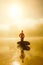 Surfer with his surfboard on a misty urban beach