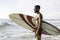 Surfer holding his surfboard on the beach - Hipster man standing on the beach and waiting big waves for surfing - Fit bearded man