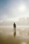 Surfer holding his surfboard on a misty urban beach