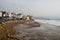 Surfer on huge wave just in front of Taghazout cityscape with fishing boats