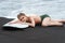 Surfer lies on surfboard on beach, eyes closed, feeling warmth of sun and gentle sway of ocean