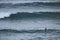 A surfer lying on his surfboard paddles over an approaching wave on a beach in Portugal