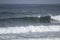 A surfer lying on his surfboard paddles over an approaching wave on a beach in Portugal