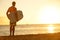 Surfer man on beach at sunset holding bodyboard