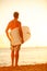 Surfer man on beach at sunset holding bodyboard