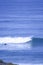 A surfer paddles on his surfboard towards a breaking approaching wave on a beach in Portugal